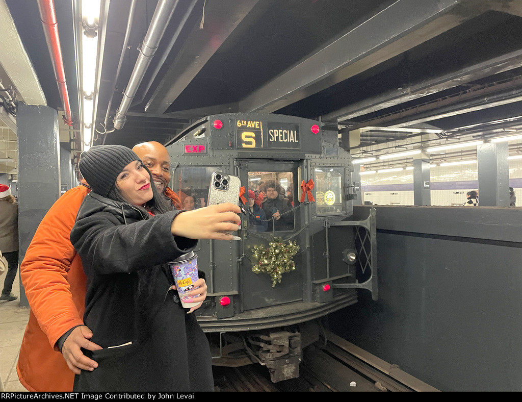 A couple posing for a selfie in front of the Holiday Train at 2nd Ave Station 